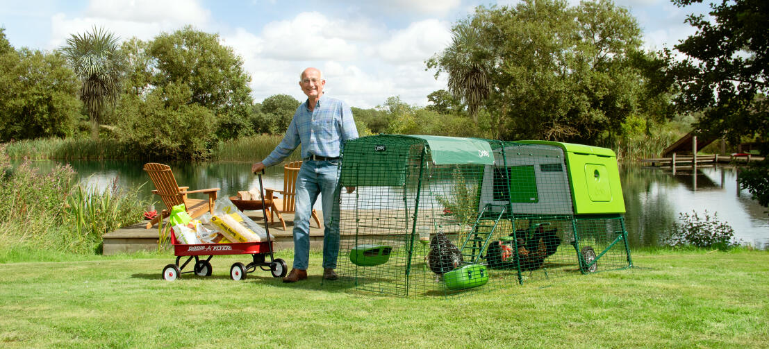 Man standing with his Eglu chicken coop in the countryside