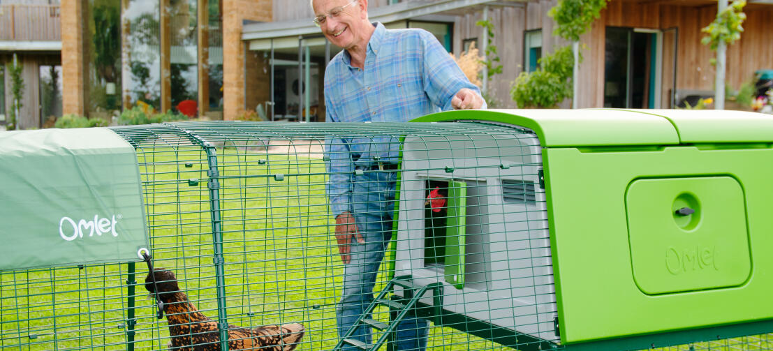 Man with large Eglu chicken coop and run in a garden