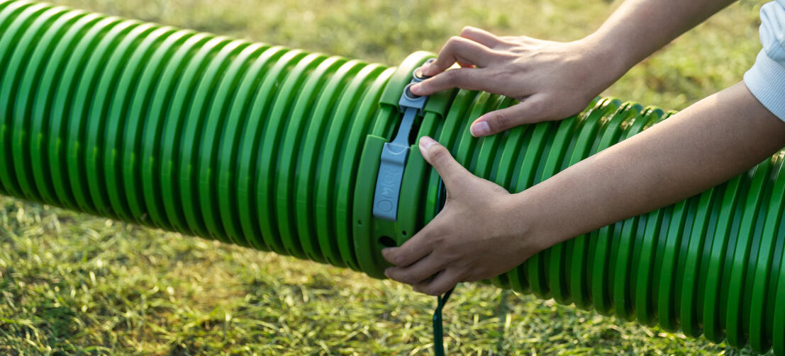 Close up of hands connecting two Zippi tunnels together using the built-in locking connectors.