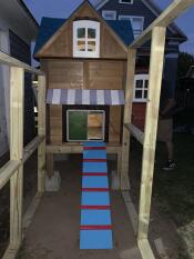 A green automatic coop door on a wooden coop