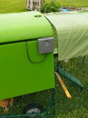 A control panel of an automatic coop door placed on the side of a plastic coop