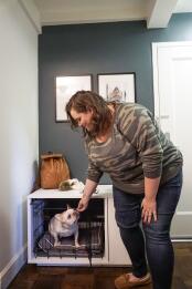 A woman petting her dog inside a Fido Nook with a wardrobe attached