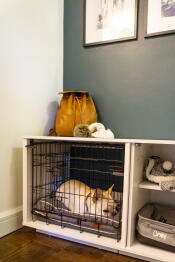 A white dog asleep inside a Fido Nook with a closet and crate