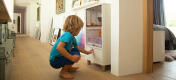 A small child using the press to open Qute hamster and gerbil cage storage compartment.