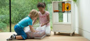 Two children playing with a hamster next to a Qute hamster cage.