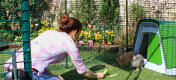 A woman feeding her bunny rabbits vegetables out of a Go hutch with a walk in run attached