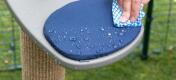 Cleaning a outdoor step with blue cushion which makes it a waterproof outdoor cat gym