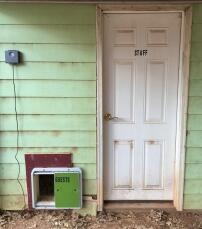 An automatic chicken door opener attached to outside of house