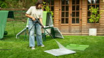 Woman pressure washing the pull out parts of the Eglu Go up chicken coop