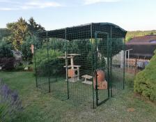 A walk in run in a garden set up for a cat with cat trees, toys and accessories