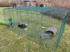 Two rabbits in their enclosure connected to a green tunnel