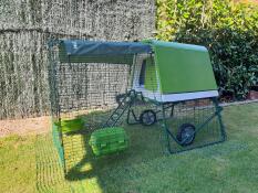 An Omlet Cube with a run extension and wheels on a garden