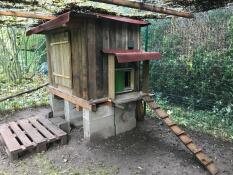 Omlet green automatic chicken coop door attached to wooden chicken coop