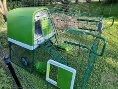 A chicken coop with a run including handles and an automatic door on the side