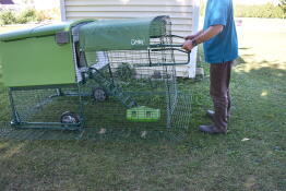 A person demonstrating how to move a chicken coop using wheels and handles