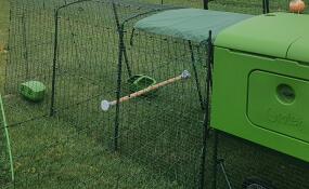 A chicken coop with a run covered by a shade