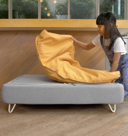 Girl taking a yellow beanbag topper off an Omlet Topology dog bed with white hairpin feet.