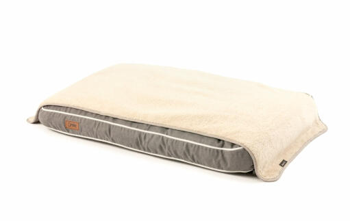 A grey Fido Studio dog bed with a plush blanket over the top