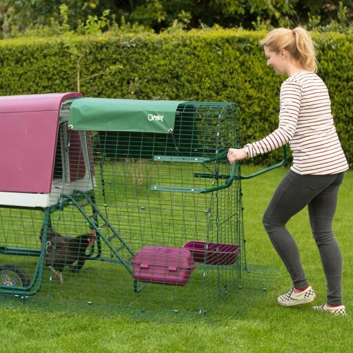 Woman moving Eglu Go up chicken coop with wheels and run handles