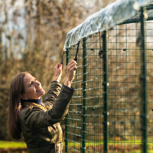 A woman attaching the cover to the walk in run