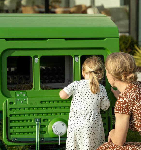 Mother and daughter looking into the triple egg port of the large Eglu pro chicken coop