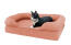A cat sitting on a pink cat bed.