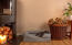 A small black dog lying on a grey memory foam bolster bed in a living room