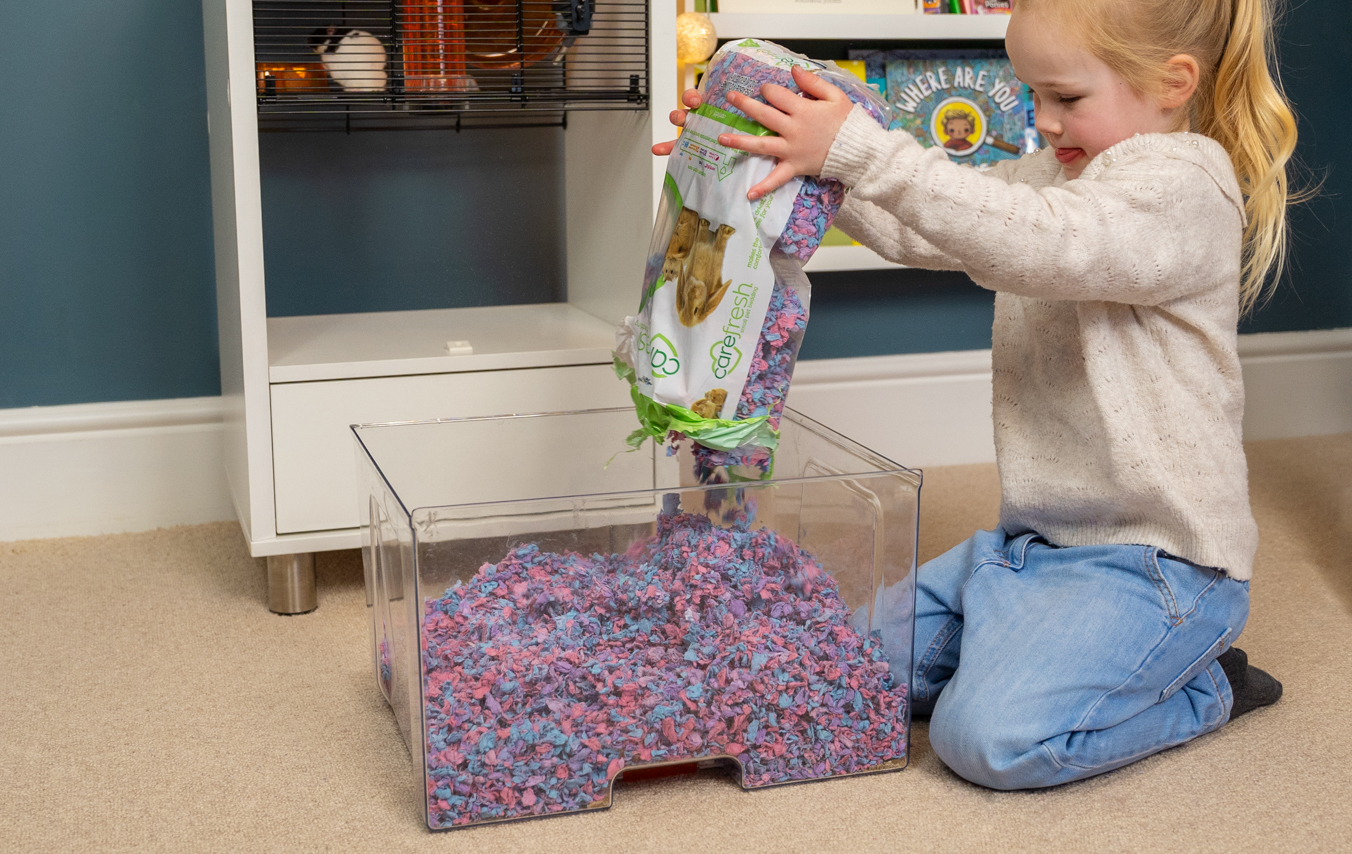 kid cleaning a hamster bedding tray of a Qute hamster cage
