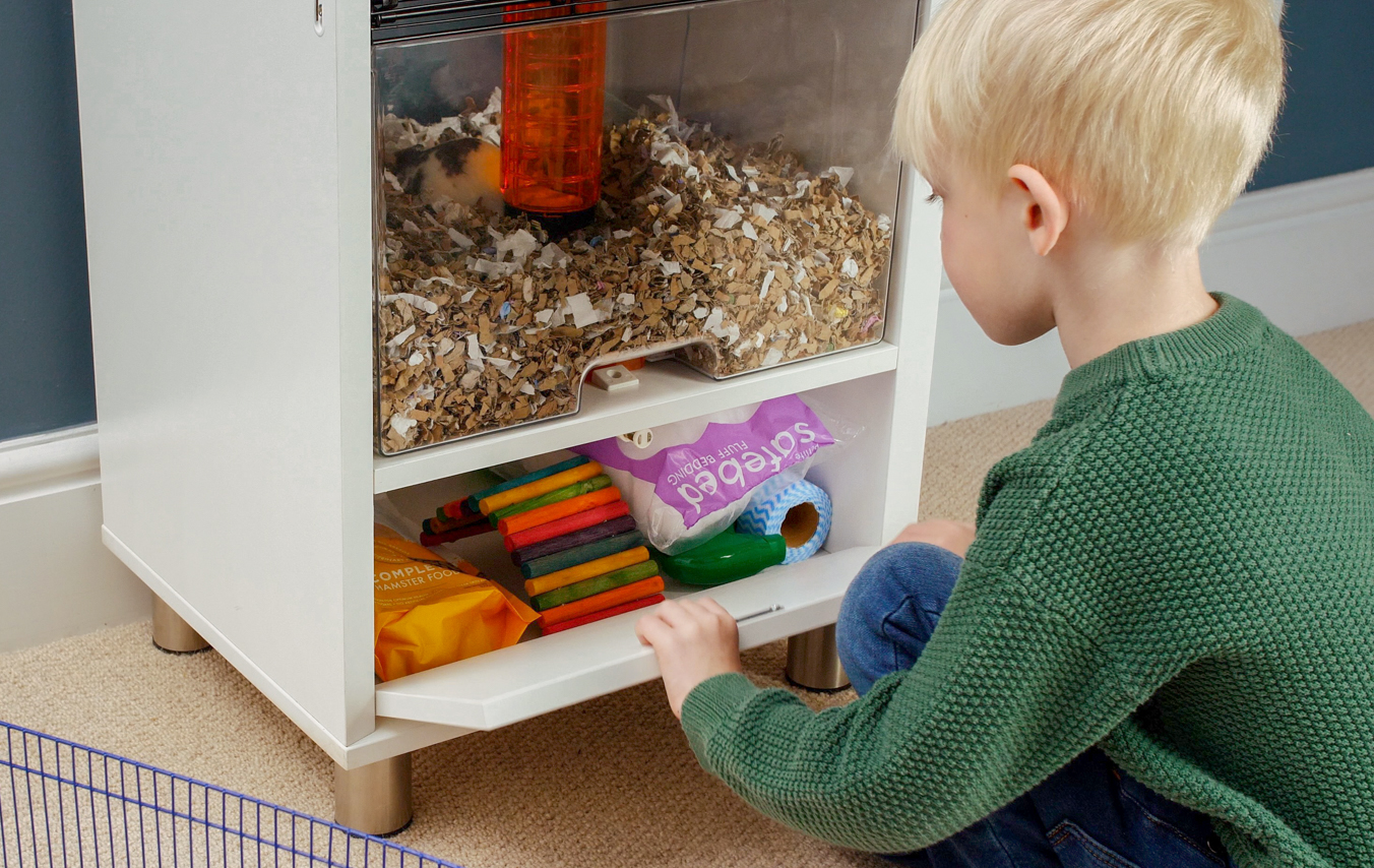 Kid storing hamster bedding in the Qute hamster cage storage space
